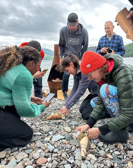 People on a rocky beach trying to start a fire.