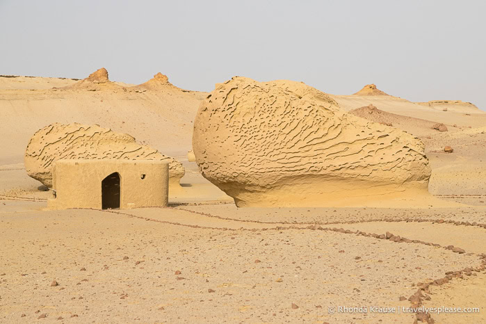 Rock formations beside a path and a shelter in Wadi Al-Hitan.