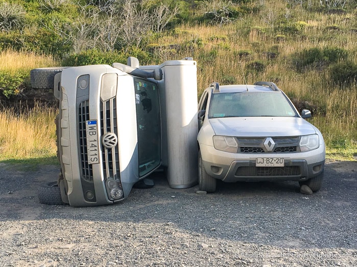 RV blown on its side next to a car.