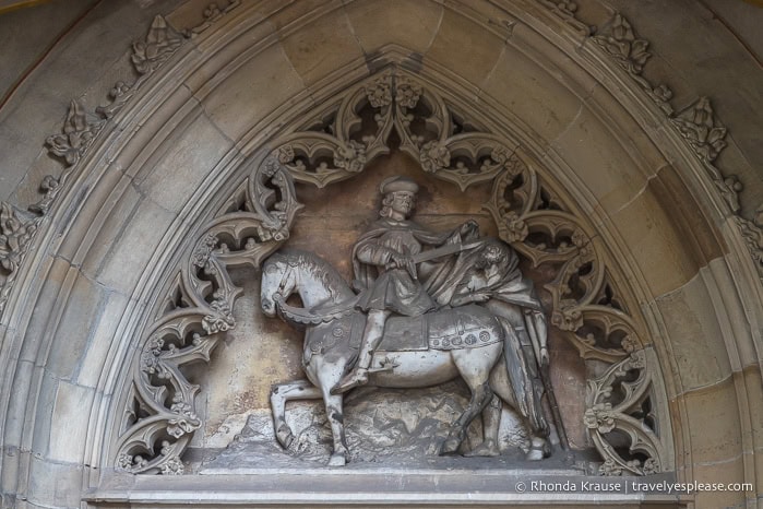 Sculpture of a man riding a horse above a doorway.