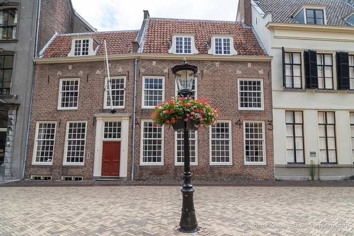 Lamp post with flowers in front of a brick building.